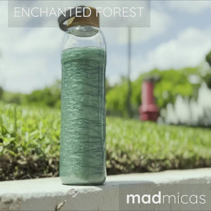 Glass bottle with green liquid on a grassy background with 'Enchanted Forest' text and 'madmicos' branding.